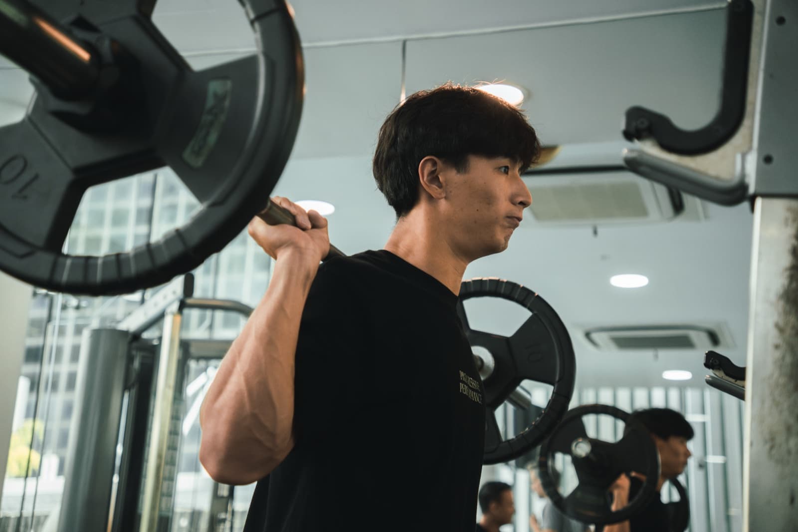 Progressive Performance team member preparing for a barbell squat in the studio.