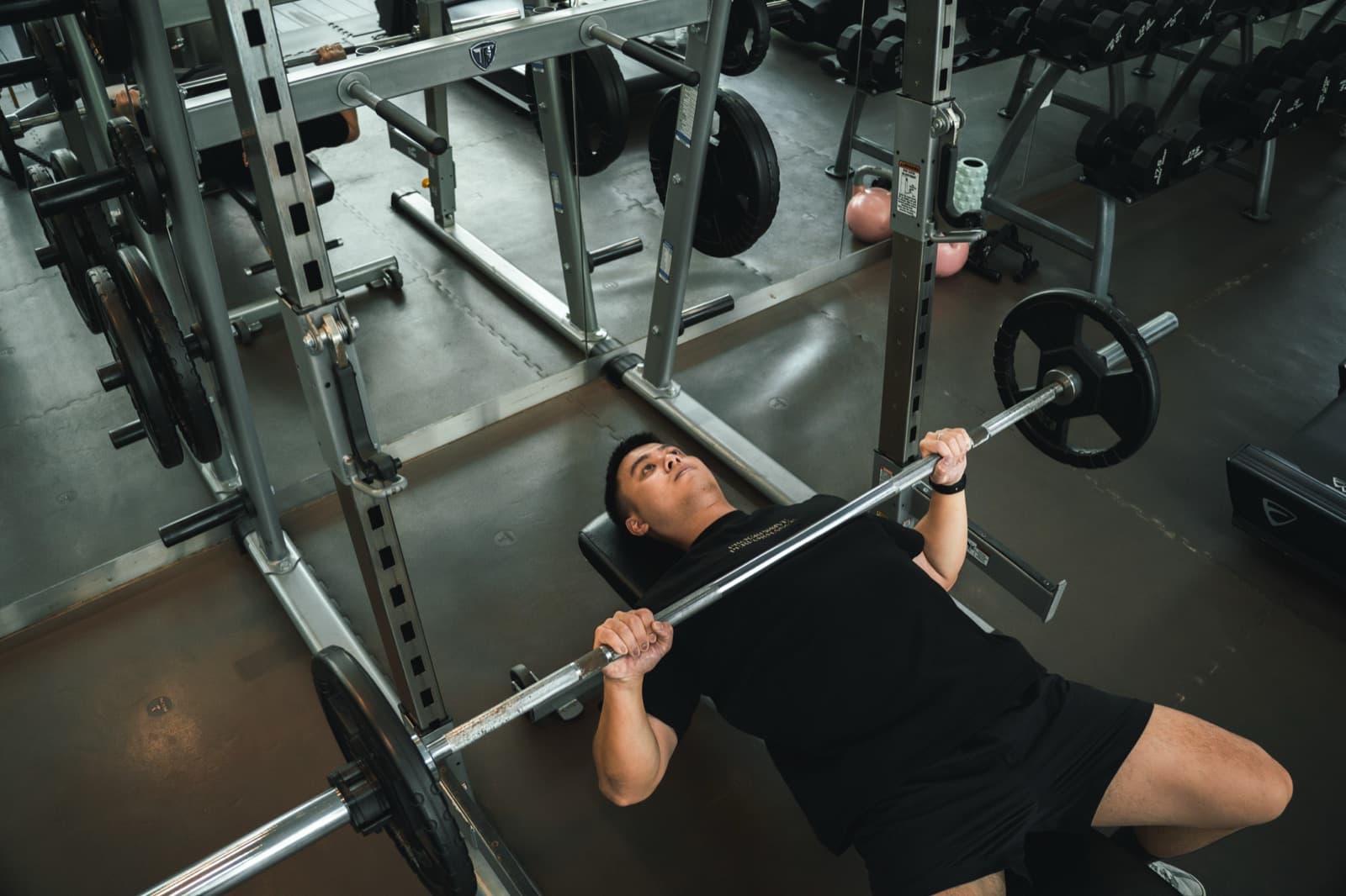 Person performing a barbell bench press in the Progressive Performance training studio