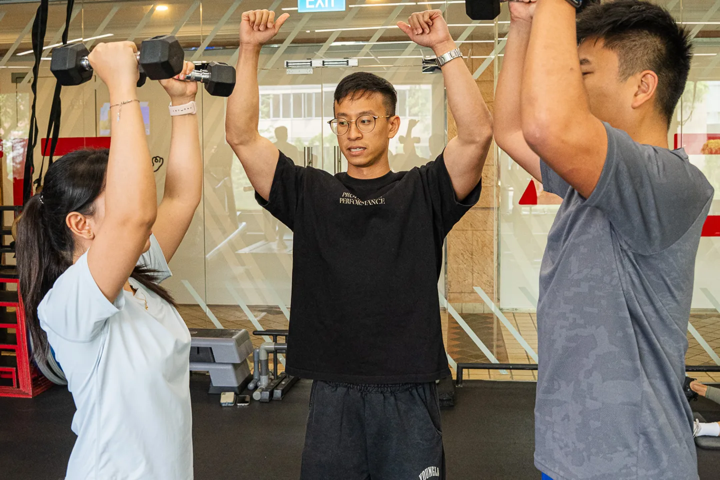 Two clients training together while Leon coaches their overhead press