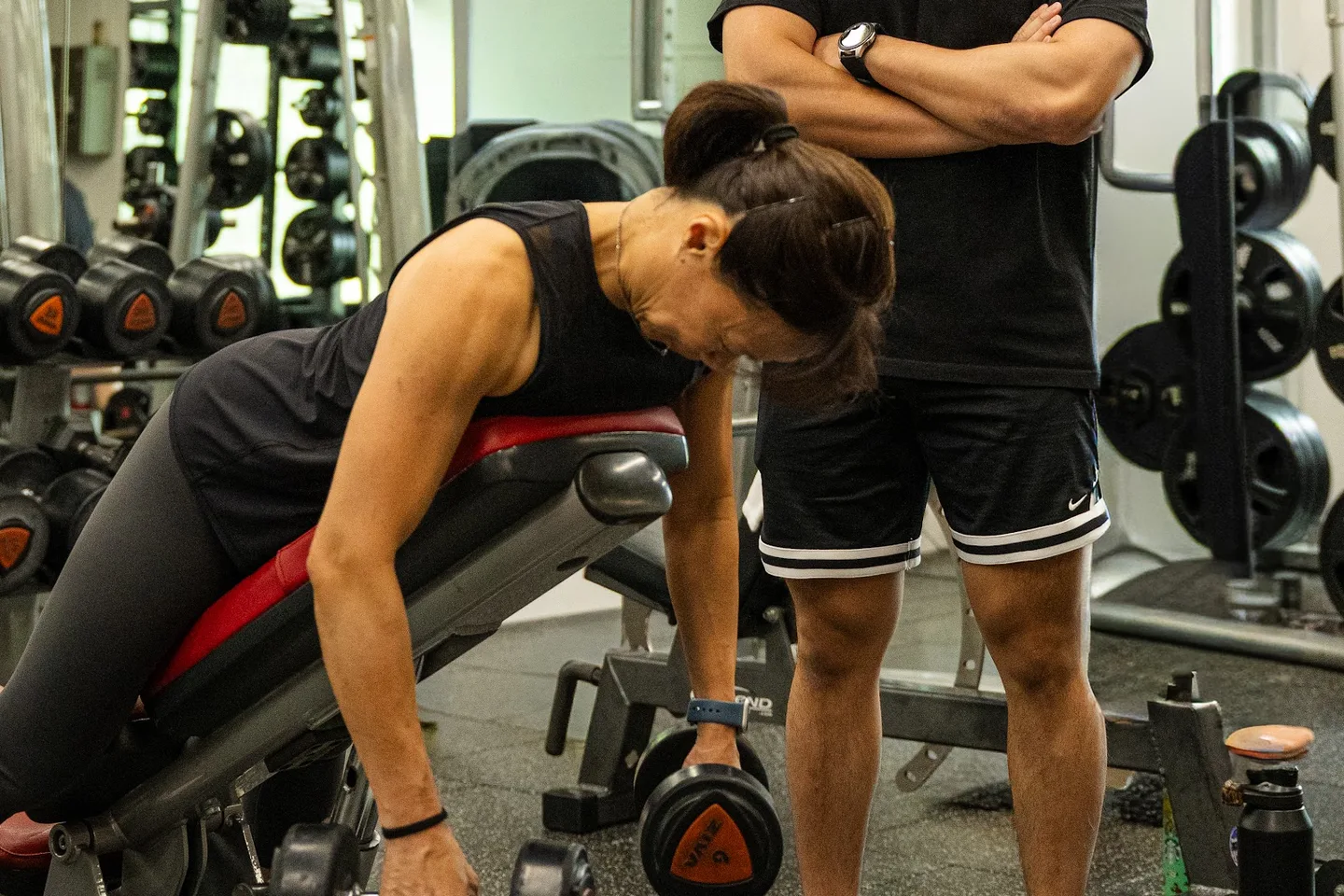 A client completing a supported dumbbell row with Kieran coaching